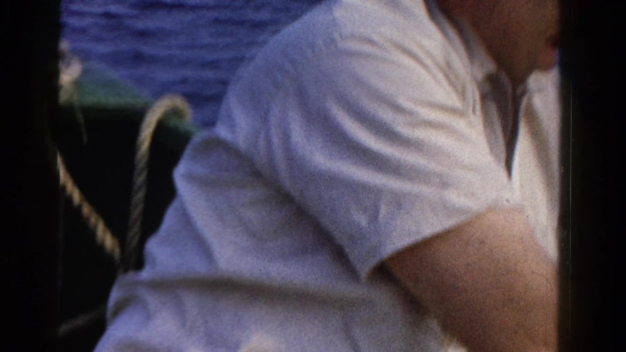 Cropped 1958 Ontario boat scene showing an adult in a white shirt near railings or rigging with water beyond.