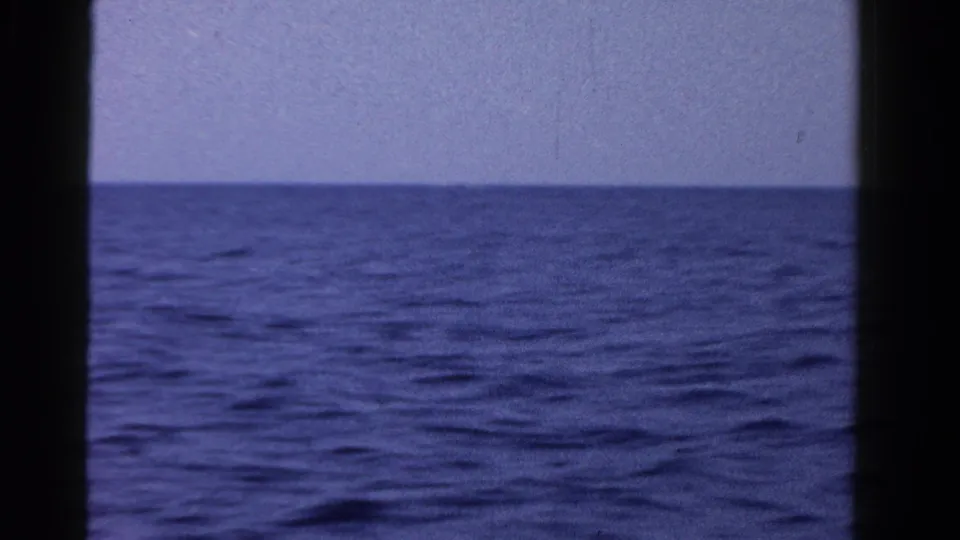 1958 8mm home-movie view of open water and pale sky in Ontario, seen through dark film-frame edges.