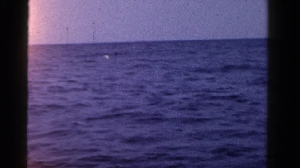 1958 Ontario 8mm frame showing mostly open water, a low horizon, and a small bright speck near the left side.