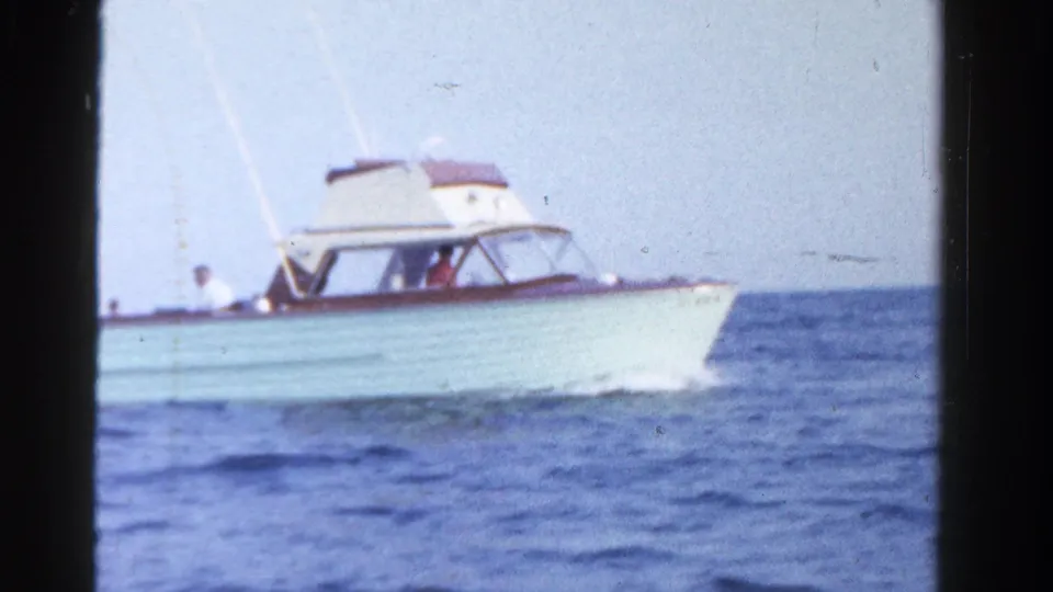 A white mid-century motor yacht with wood trim moves across open water in the Ontario 1958 footage.