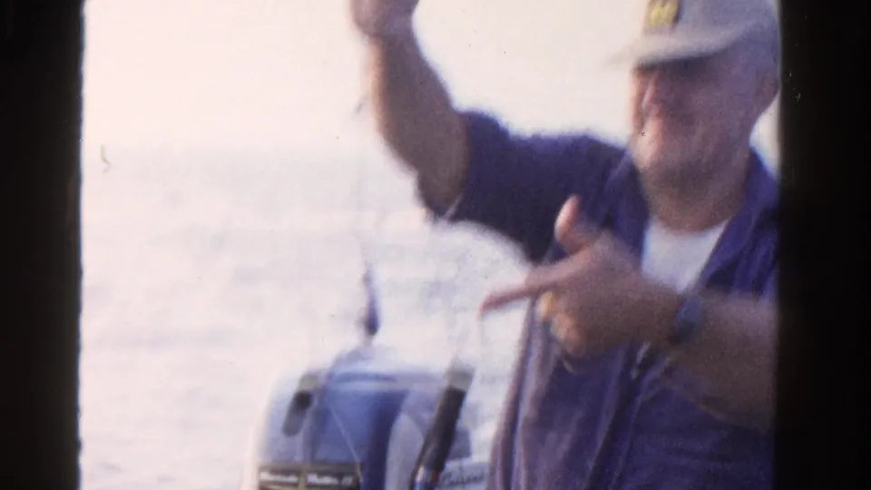 In the final frame, the man gestures animatedly from the boat while the lake and outboard motor remain visible behind him.