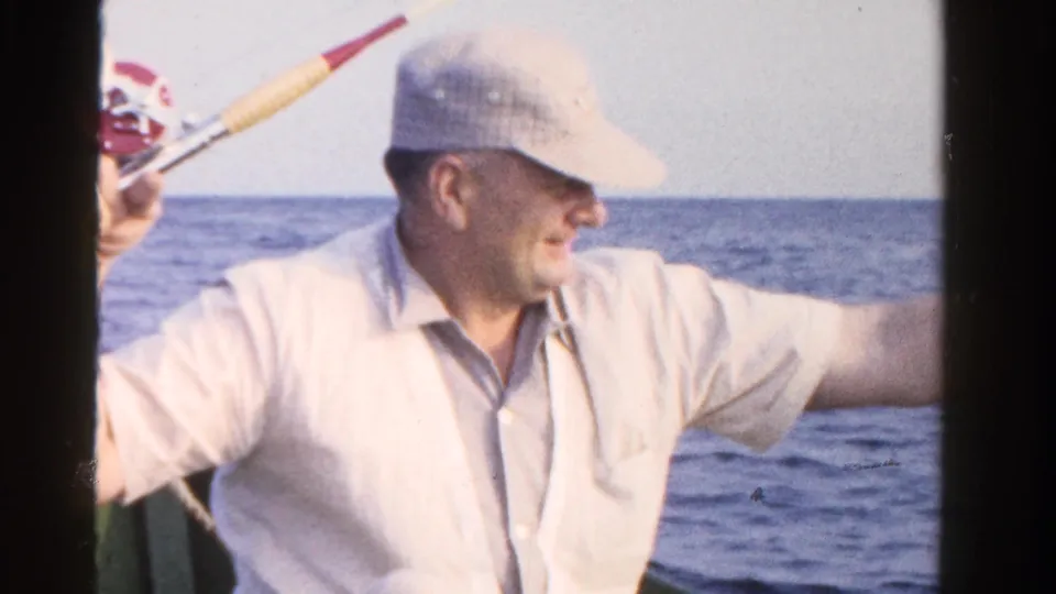 The older man appears to handle the rod or line on a boat during a 1958 Ontario fishing scene.