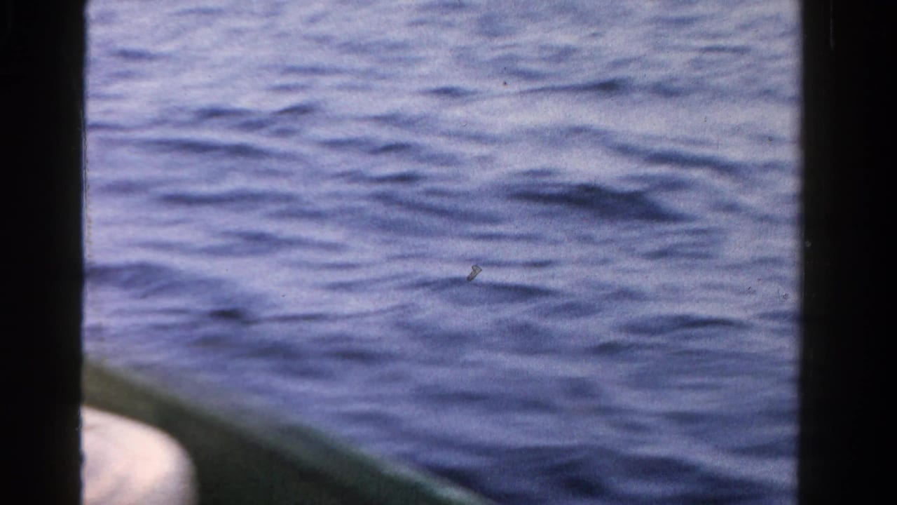 Calm Ontario water in 1958 home-movie footage, framed from a small boat with visible 8mm film edges.