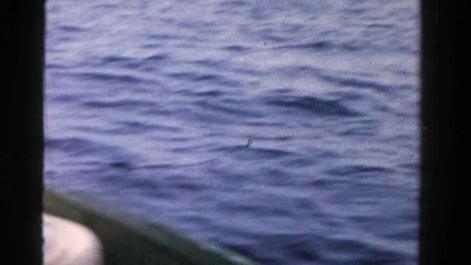 Calm Ontario water in 1958 home-movie footage, framed from a small boat with visible 8mm film edges.