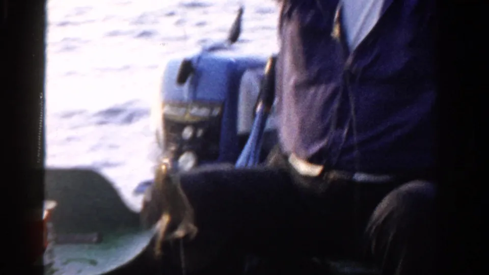 Two men sit partly out of frame in a small boat on an Ontario lake, with an outboard motor visible behind them.