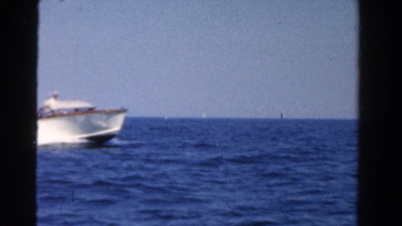 White speedboat partly entering frame on blue open water under a bright sky.