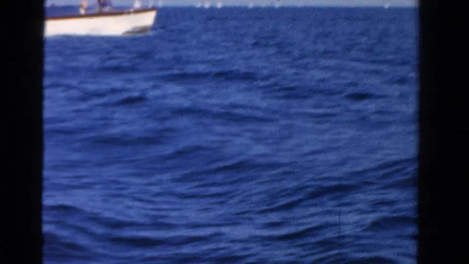 Open blue water fills the frame, with part of a small white boat visible near the upper edge in this Ontario home-movie shot.