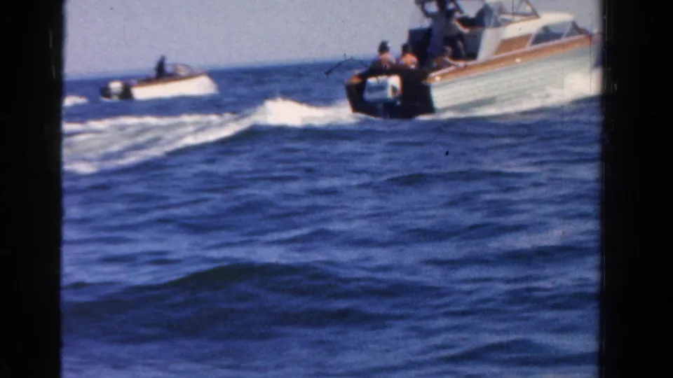 Two small motorboats move across open blue water in a 1958 Ontario home-movie boating scene.