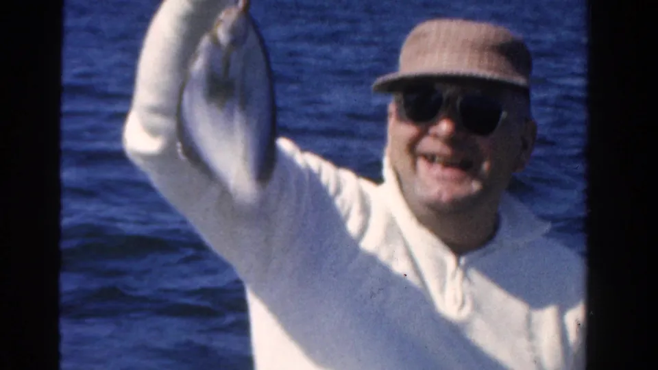 The fisherman smiles broadly while displaying the fish in this 1958 Ontario home-movie frame.