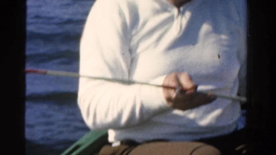 A cropped view shows the fisherman in a white long-sleeved shirt holding a rod while seated in a small boat in Ontario.