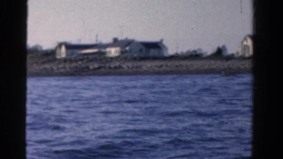 A handheld 8mm view from the boat shows rippled bay water and distant Ontario shoreline buildings in soft focus.