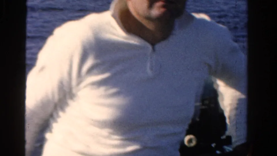 Adult man in a white long-sleeved shirt appears near the camera during an Ontario lake fishing outing in 1958 home-movie footage.