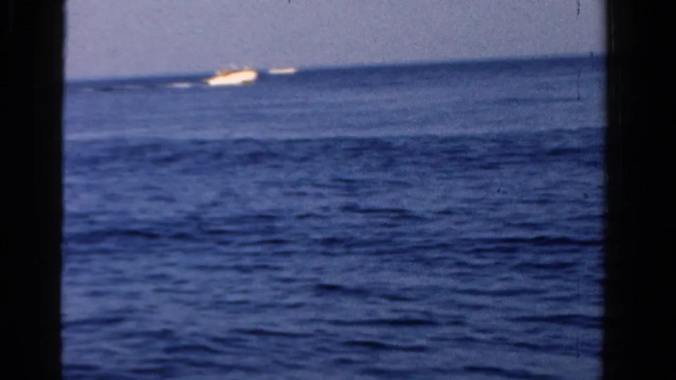 Open Ontario water fills the frame, with a small white motorboat visible in the distance in 1958 8mm footage.