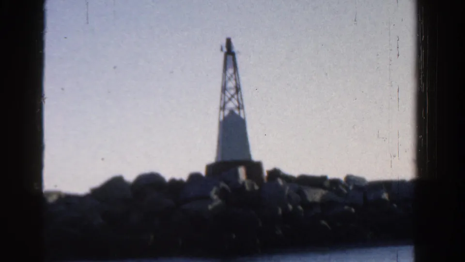 The clip ends on a rocky breakwater with a small beacon or lighthouse-like structure silhouetted against the sky.