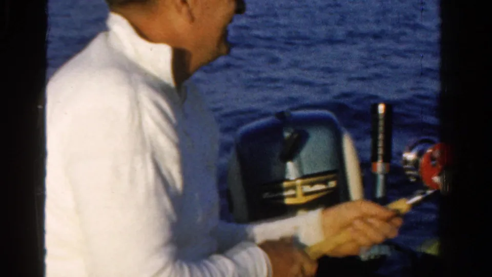 Man fishing from a small boat on an Ontario lake in 1958, with an outboard motor partly visible behind him.