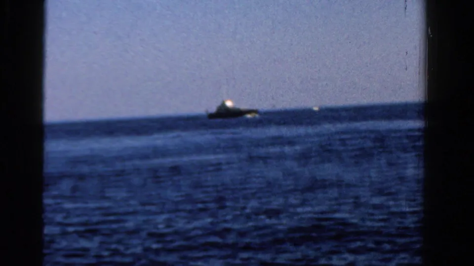 Wide view across an Ontario lake in 1958, with a small distant boat on the horizon and calm blue water.