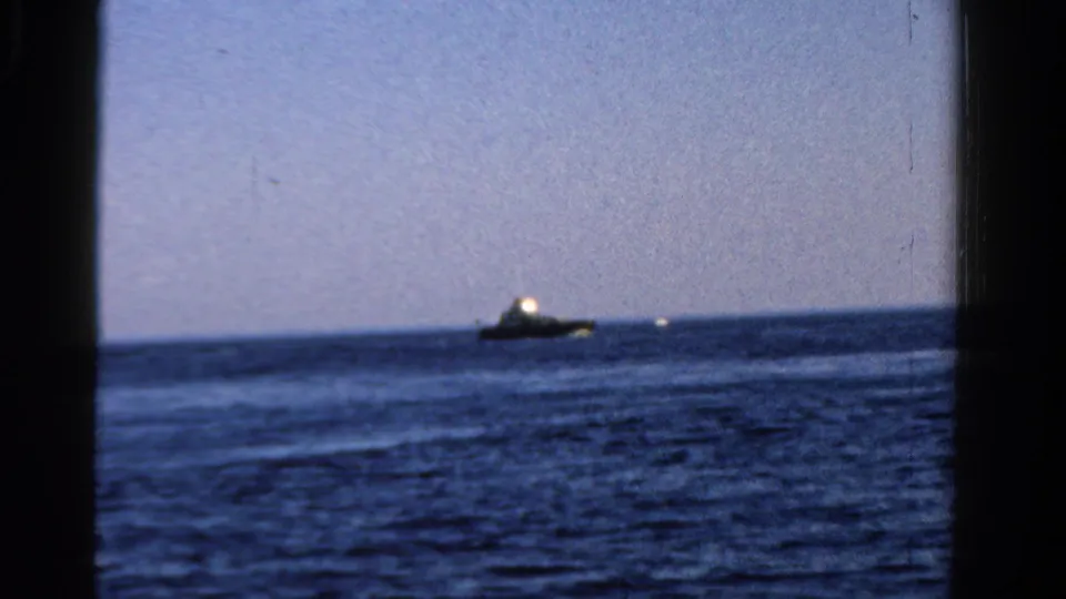 Wide 1958 Ontario lake shot showing a small boat on the water, framed by dark film edges and visible grain.