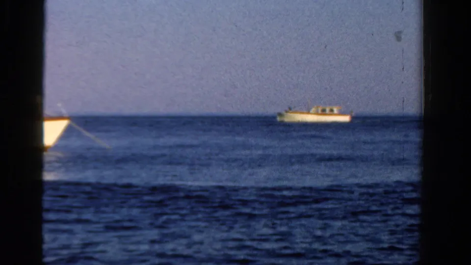 A wider 1958 Ontario lake view shows a small boat moving across calm blue water under a clear sky.