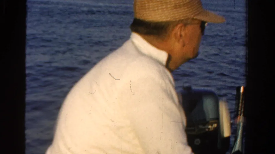 The 1958 Ontario footage shows the man from behind, seated in the boat with water filling the background.