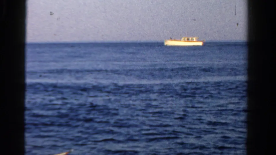 The white boat appears farther across the water, framed by 8mm grain and a steady horizon in the Ontario clip.