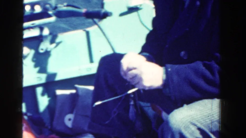 Close 8mm view of hands and boat fittings inside a small rowboat on an Ontario lake, with the seated figure partly cropped.