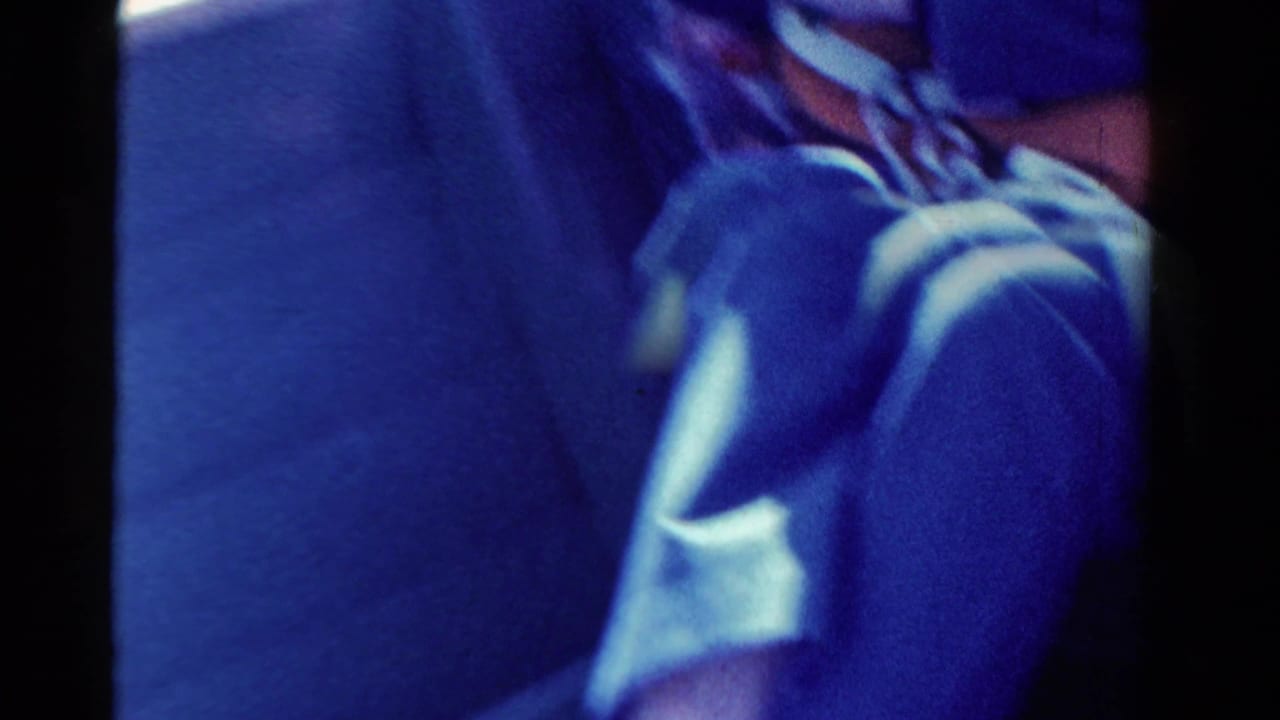 A close, partially obscured 8mm frame shows the seated figure and boat interior during the Ontario fishing outing.