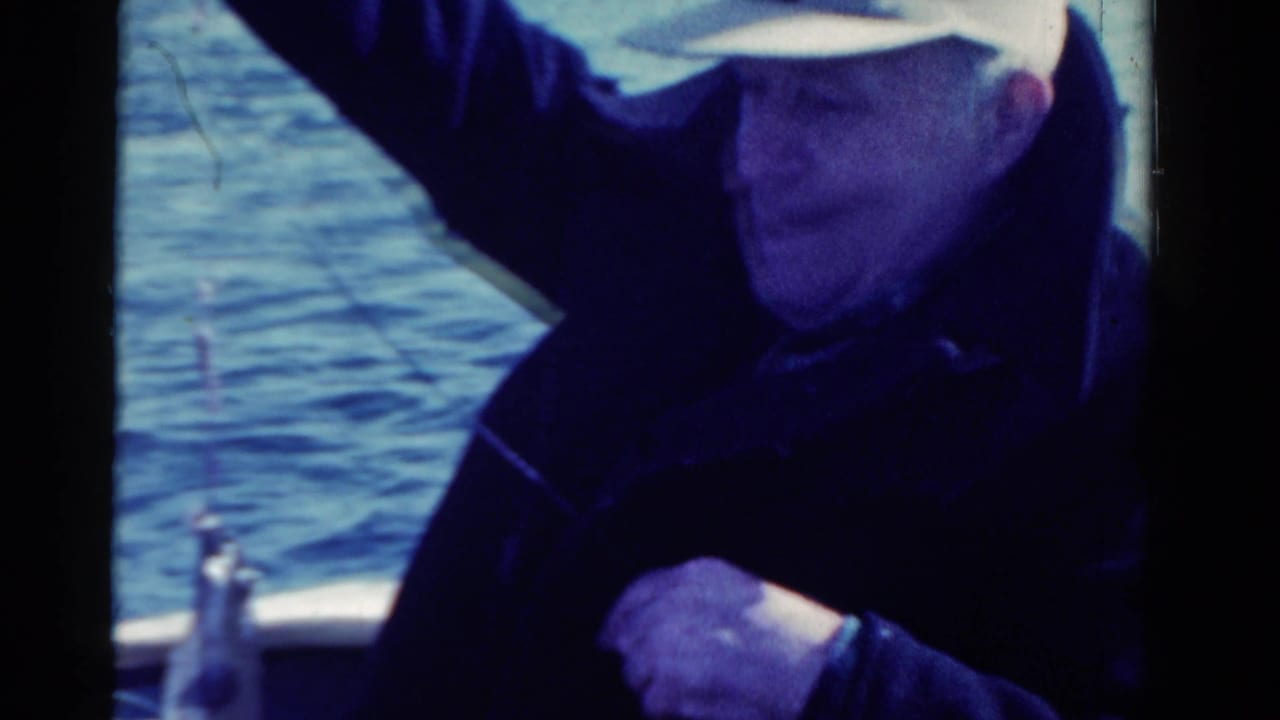 Adult man in a light cap sits aboard a boat during a 1958 Ontario fishing outing captured on 8mm film.