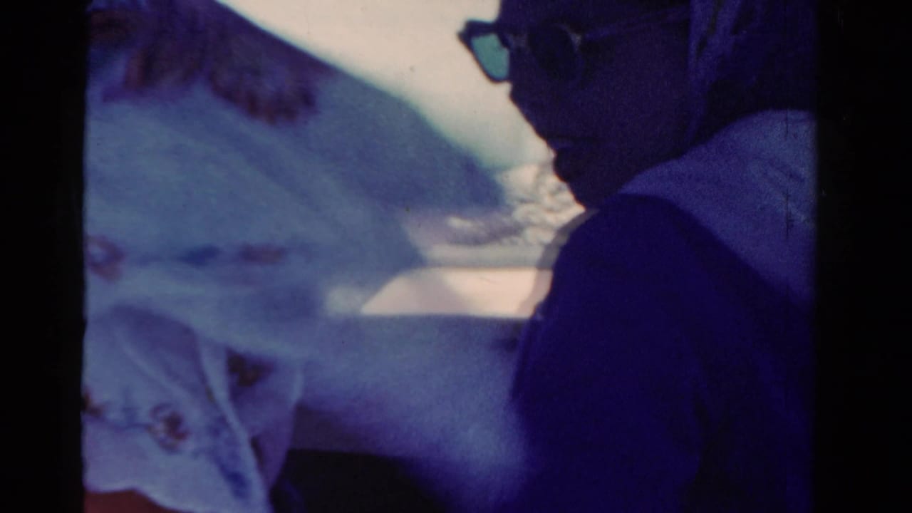 Passenger in sunglasses seated in a boat beside a person in a light patterned headscarf.