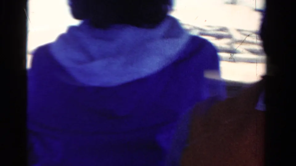 Cropped 1958 Ontario 8mm frame showing a woman in blue clothing seated on a boat in bright daylight.
