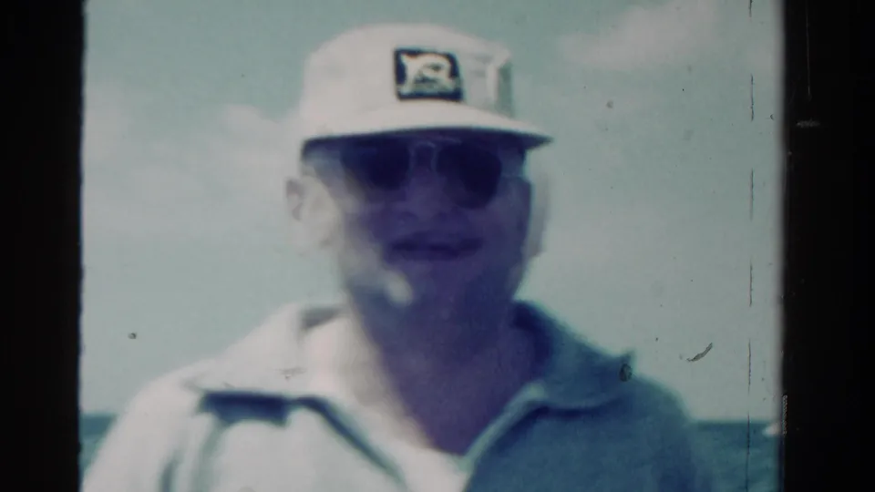 A centered close view shows the man on the boat, softly focused with visible 8mm grain and pale color shift.