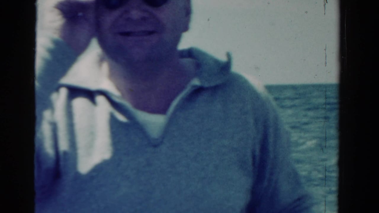 Adult man in a light cap and collared shirt faces the camera on a boat in supported 1958 Ontario home-movie footage.