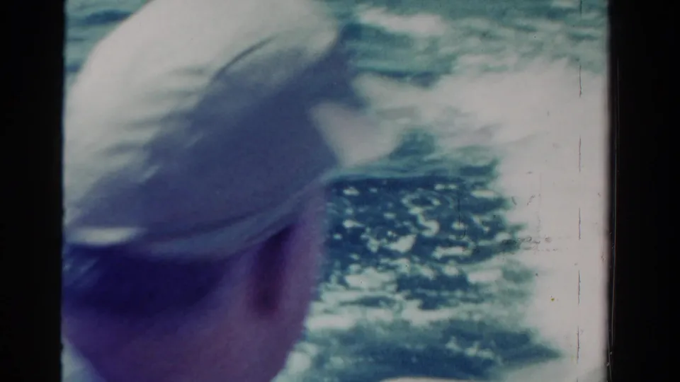 Rear view of the man in a light cap looking out over the water from a boat in supported 1958 Ontario footage.