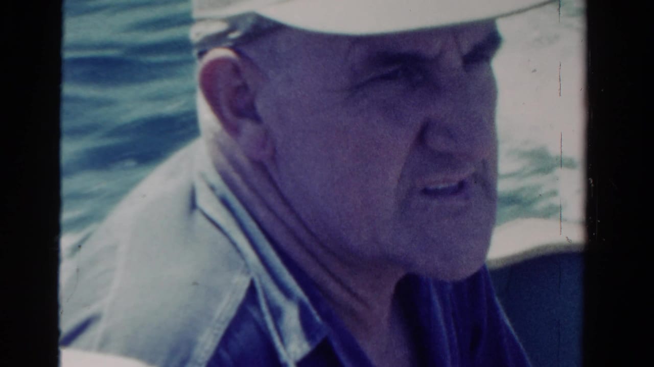 Older man in a pale cap and collared shirt aboard a boat in Ontario, Canada, based on supplied 1958 home-movie metadata.