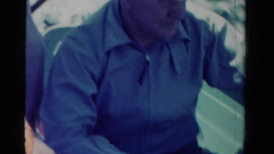Man in a light collared shirt sits aboard the boat as water passes alongside, from the supplied 1958 Ontario home-movie clip.
