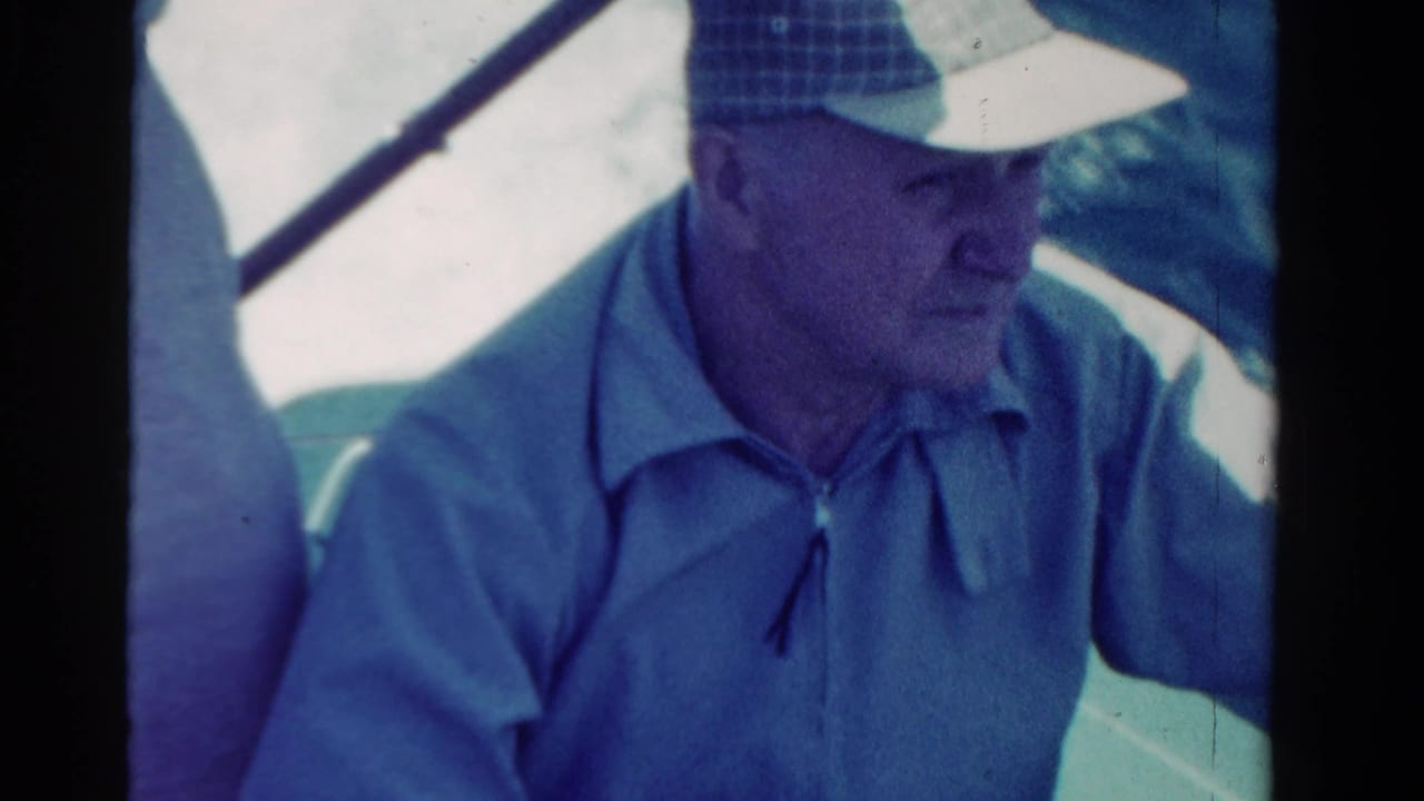 Adult man in a checkered cap looking down inside a car.