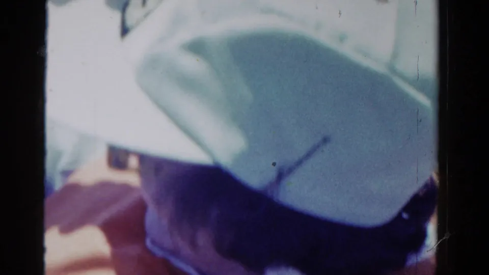 1958 Ontario 8mm frame with a close side view of the woman's white hat and sunglasses during a sunny ride.