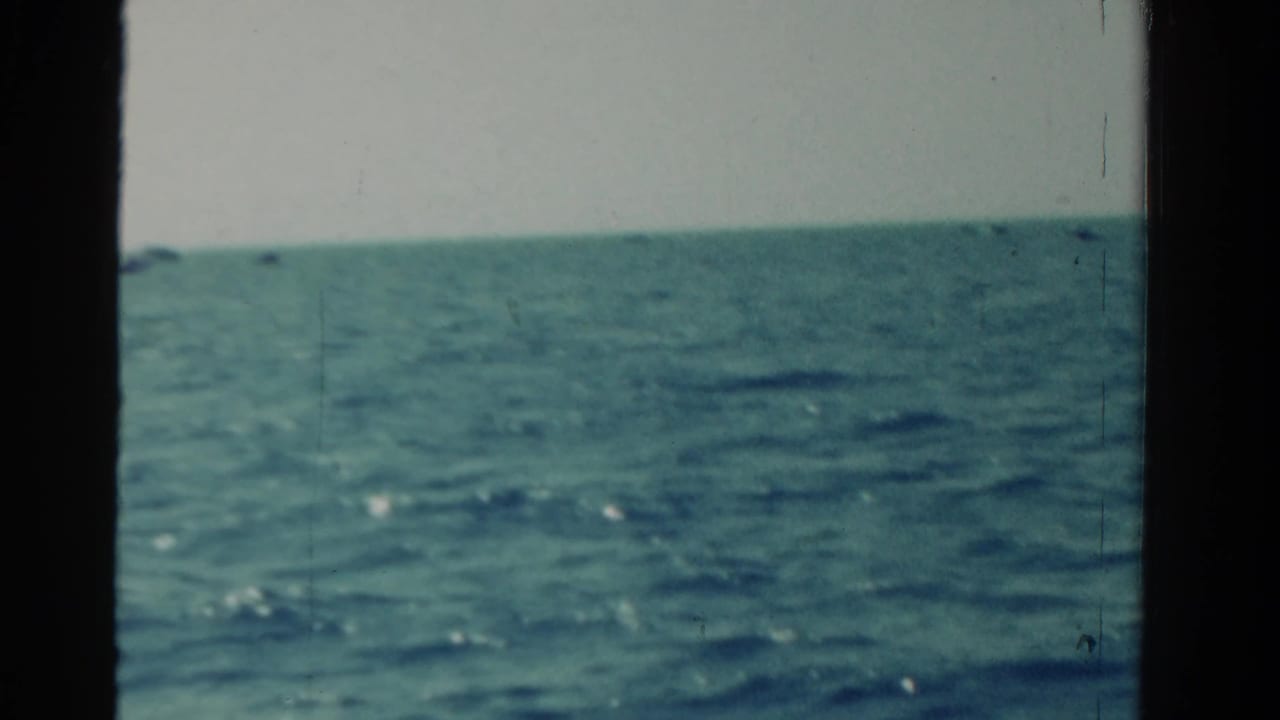 1958 Ontario 8mm frame showing open blue-green water and a low horizon, viewed through dark vessel or window edges.