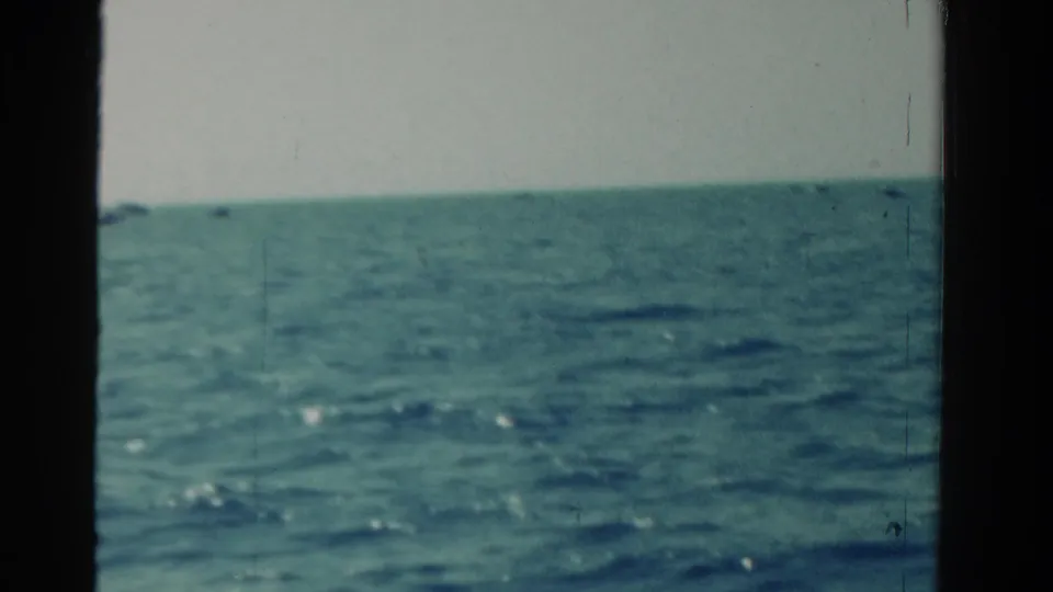 1958 Ontario 8mm frame showing open blue-green water and a low horizon, viewed through dark vessel or window edges.