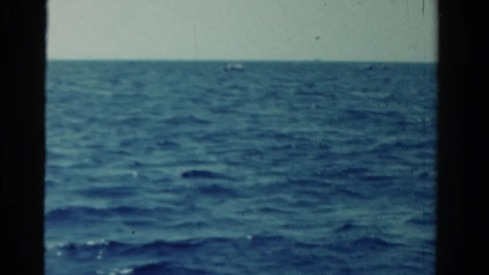 1958 Ontario 8mm frame showing a wide expanse of blue water beneath a pale sky from a moving-vessel viewpoint.