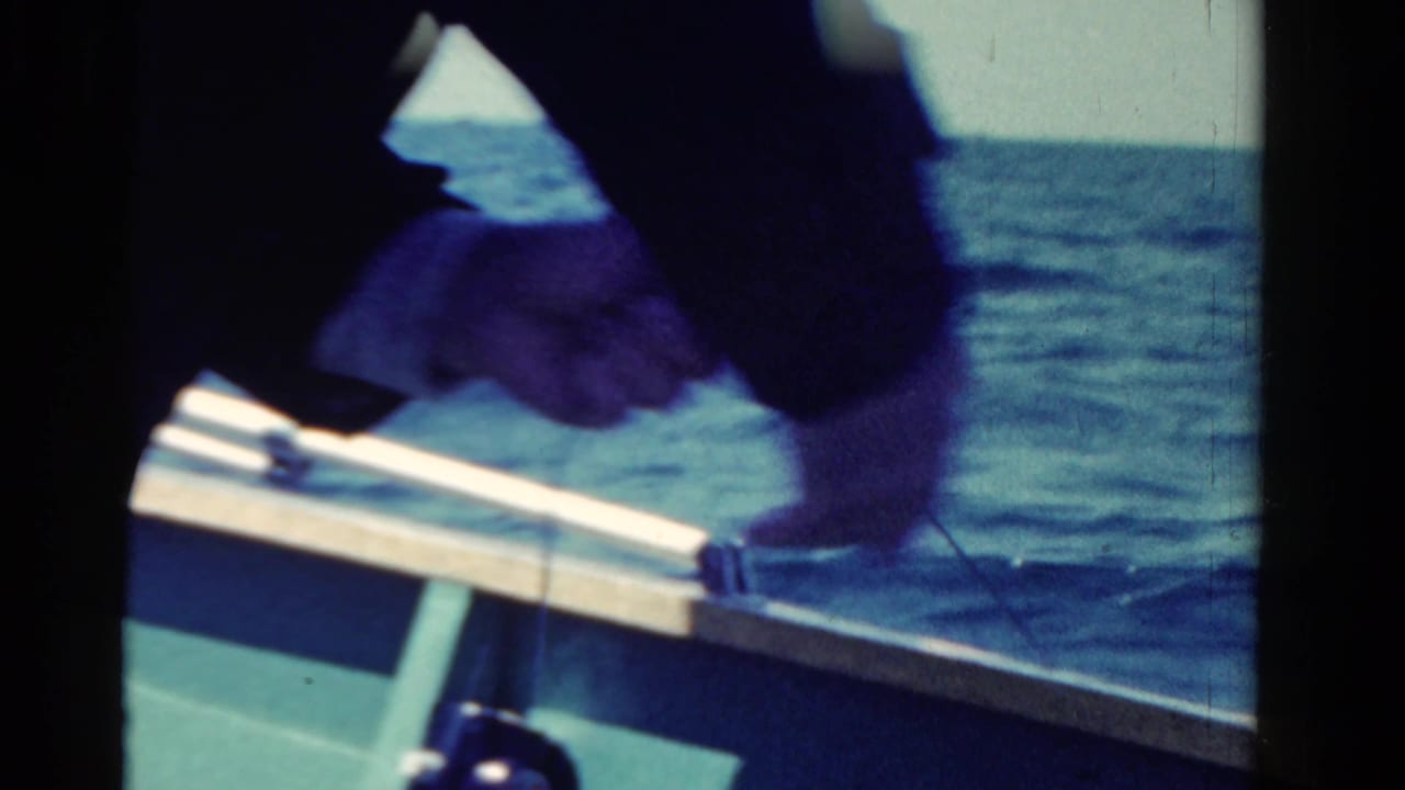 A close 8mm view of a person handling a fishing line over the side of a small boat in Ontario, Canada.