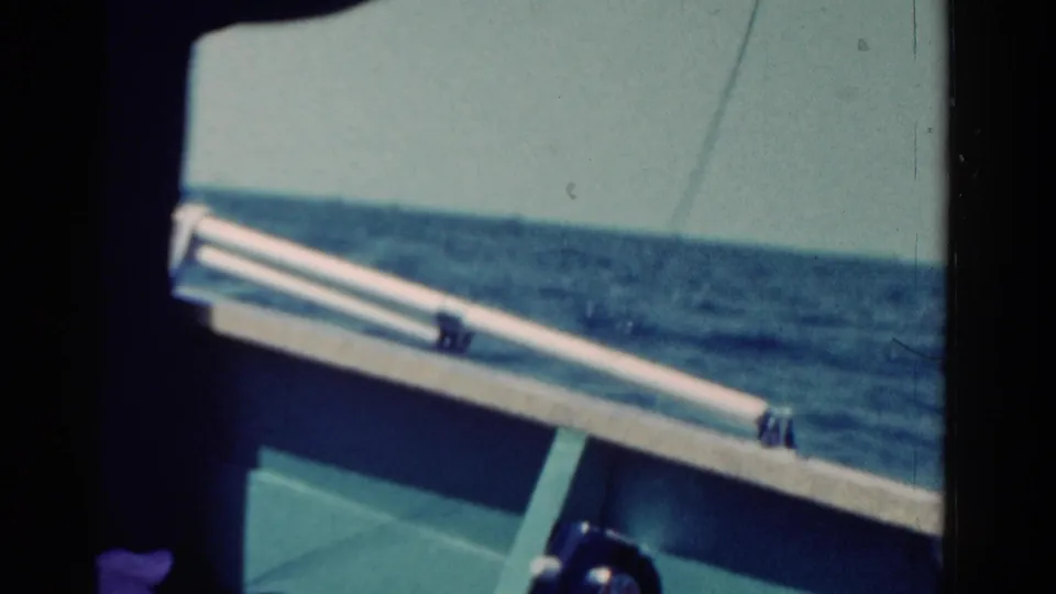 An 8mm home-movie frame holds on the boat edge and fishing line, with Ontario open water stretching into the distance.