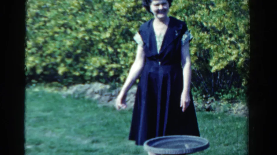The woman stands facing the camera in an Ontario garden, with a birdbath partly visible in the foreground.