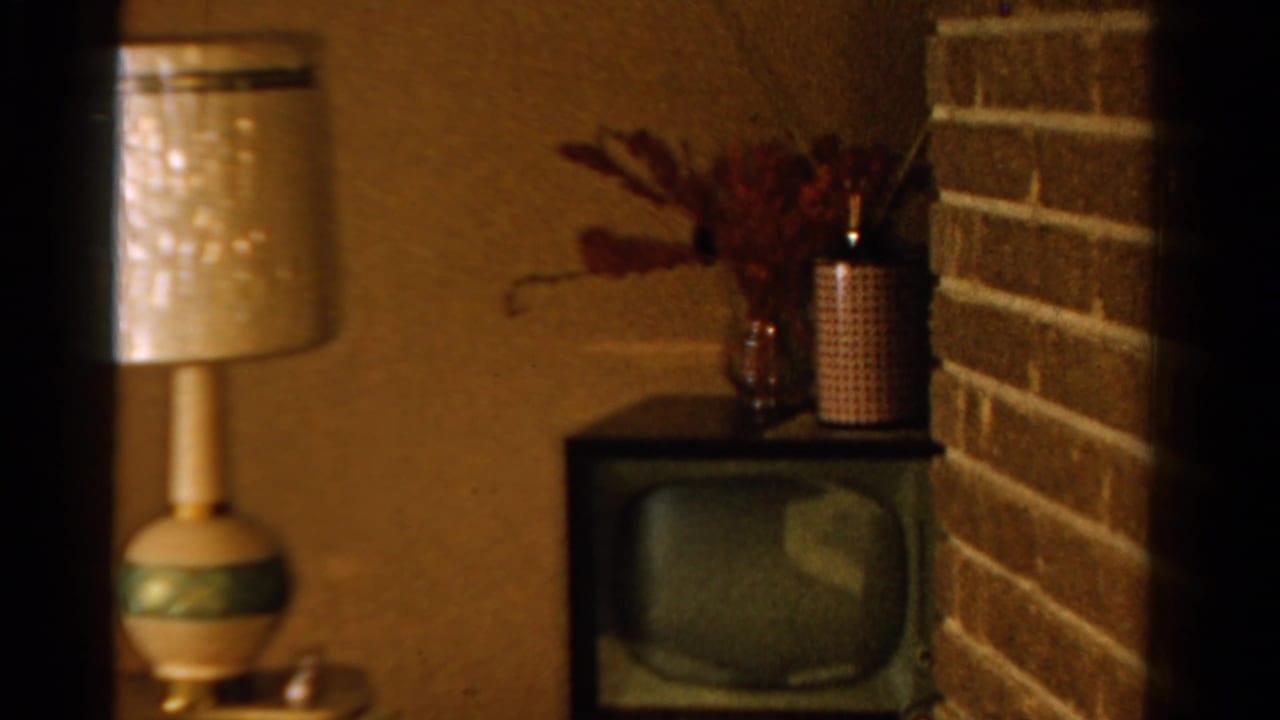 1958 Ontario home interior with a patterned table lamp beside a vintage television near a brick wall.