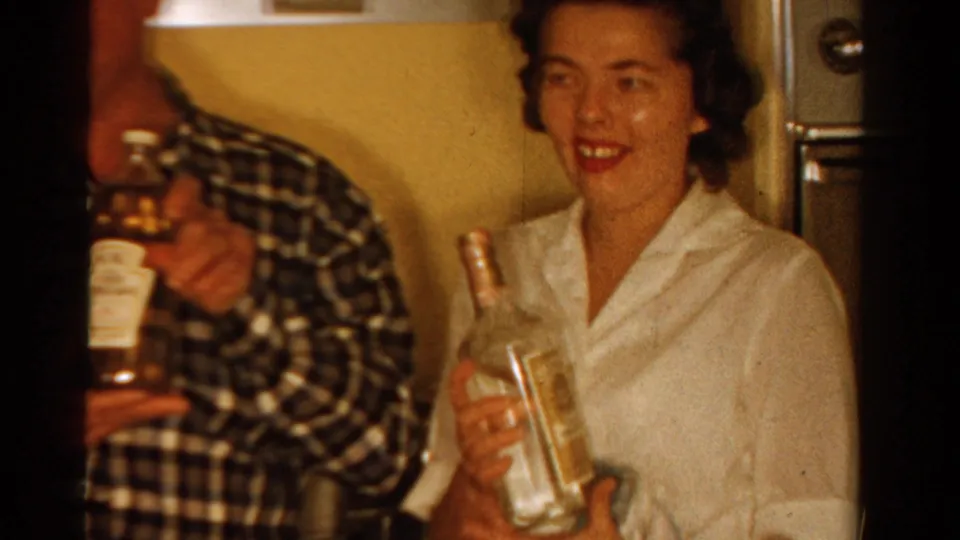 1958 Ontario kitchen frame with a smiling woman holding a clear bottle beside a partly cropped man with another labeled bottle.