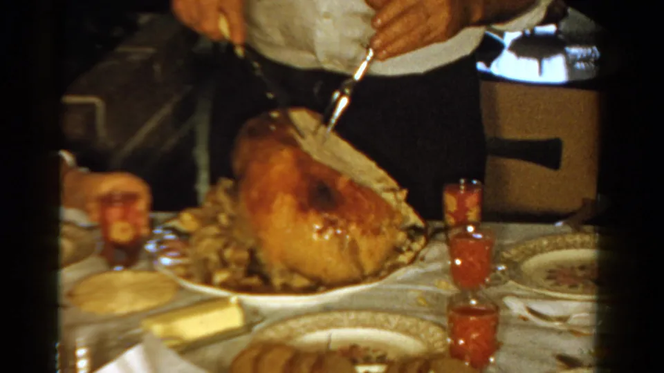 The turkey is carved at a 1958 Ontario dinner table, with hands, plates, side dishes, and red condiment glasses in view.