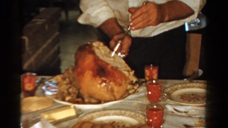 A white-shirted adult carves the holiday turkey in this 1958 Ontario private home dinner scene.