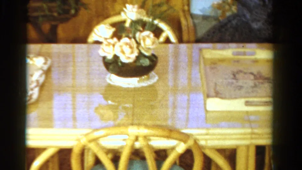 A table setting in the Ontario home includes a vase of roses, reflective tabletop, chair back, placemat, and decorative box.