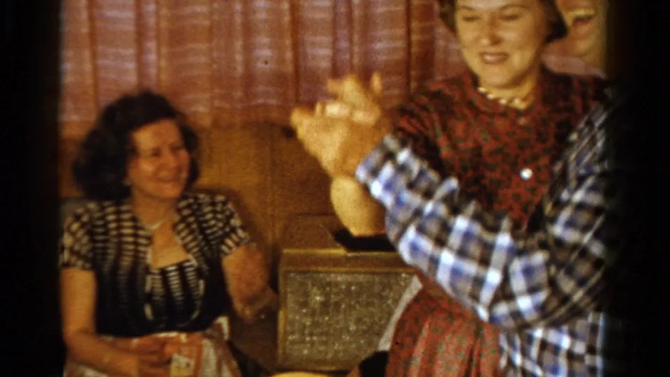A seated guest watches the couple dance in a wood-paneled Ontario home-party room from 1958.