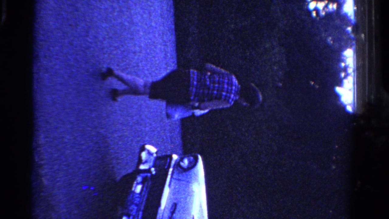 The woman moves farther along the pavement in blue light while the pale car remains partly visible below her.