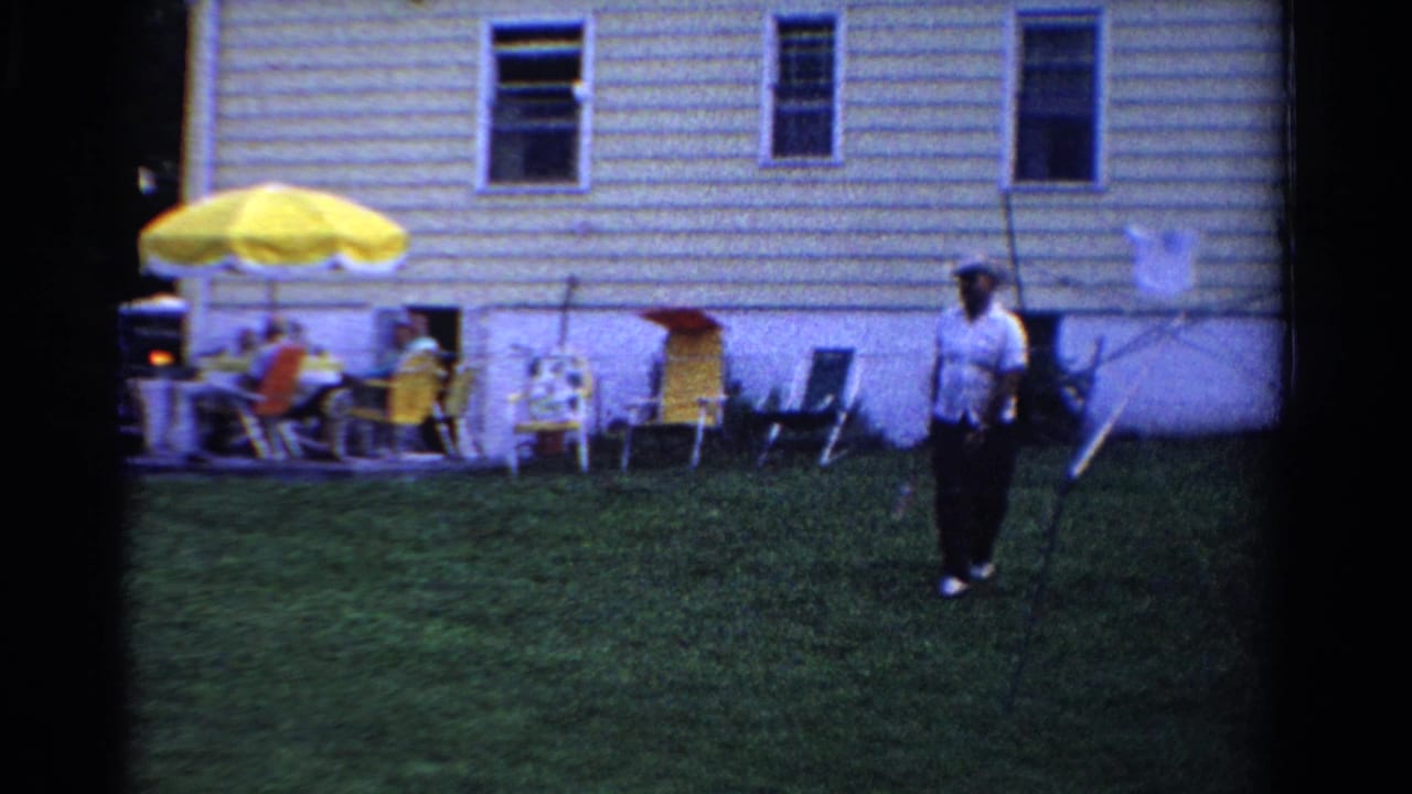 A 1958 Ontario backyard scene shows an adult holding a racket, with guests seated under a bright yellow patio umbrella.
